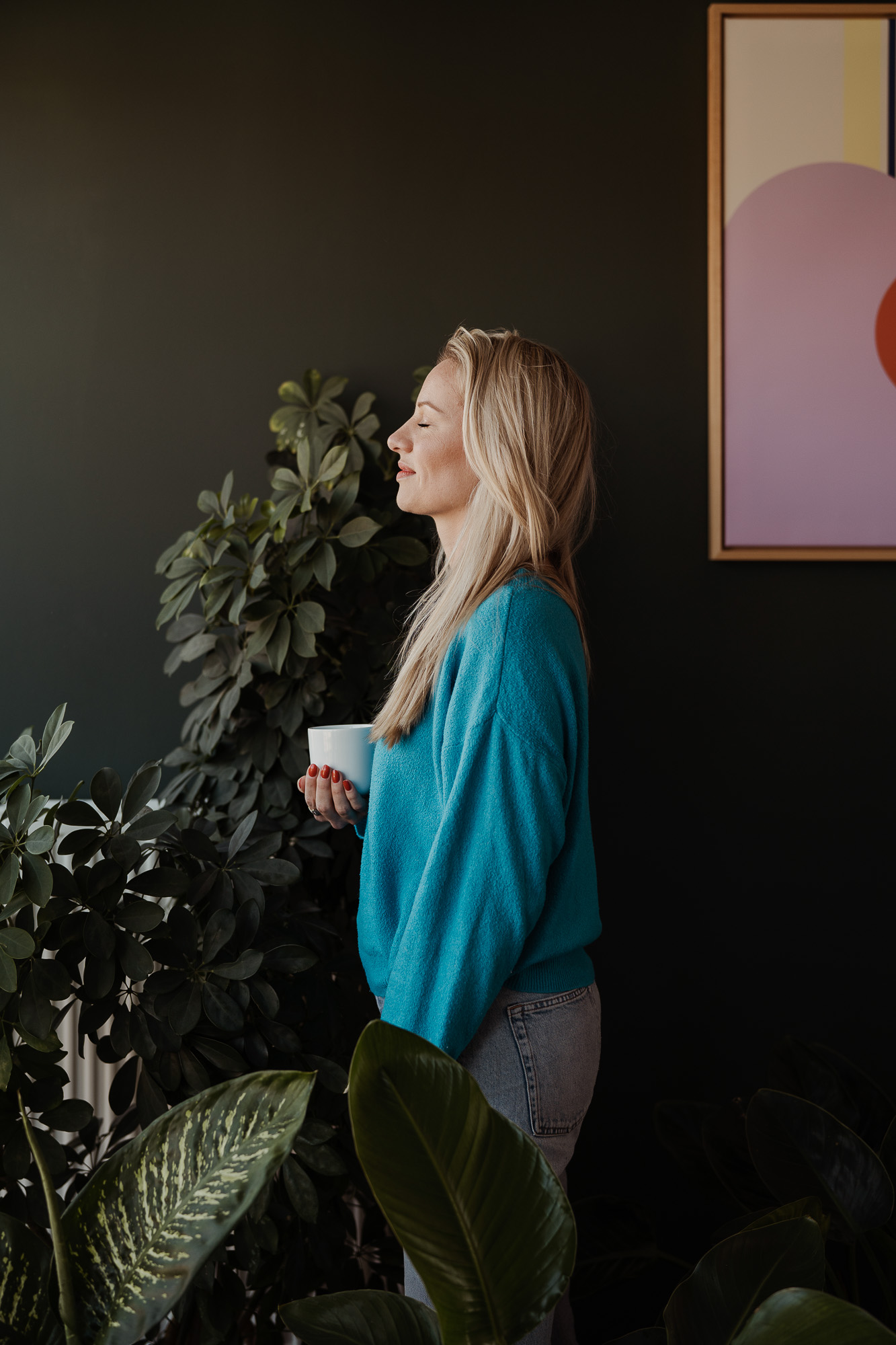 Portrait einer Frau mit Tasse zwischen grünen Pflanzen