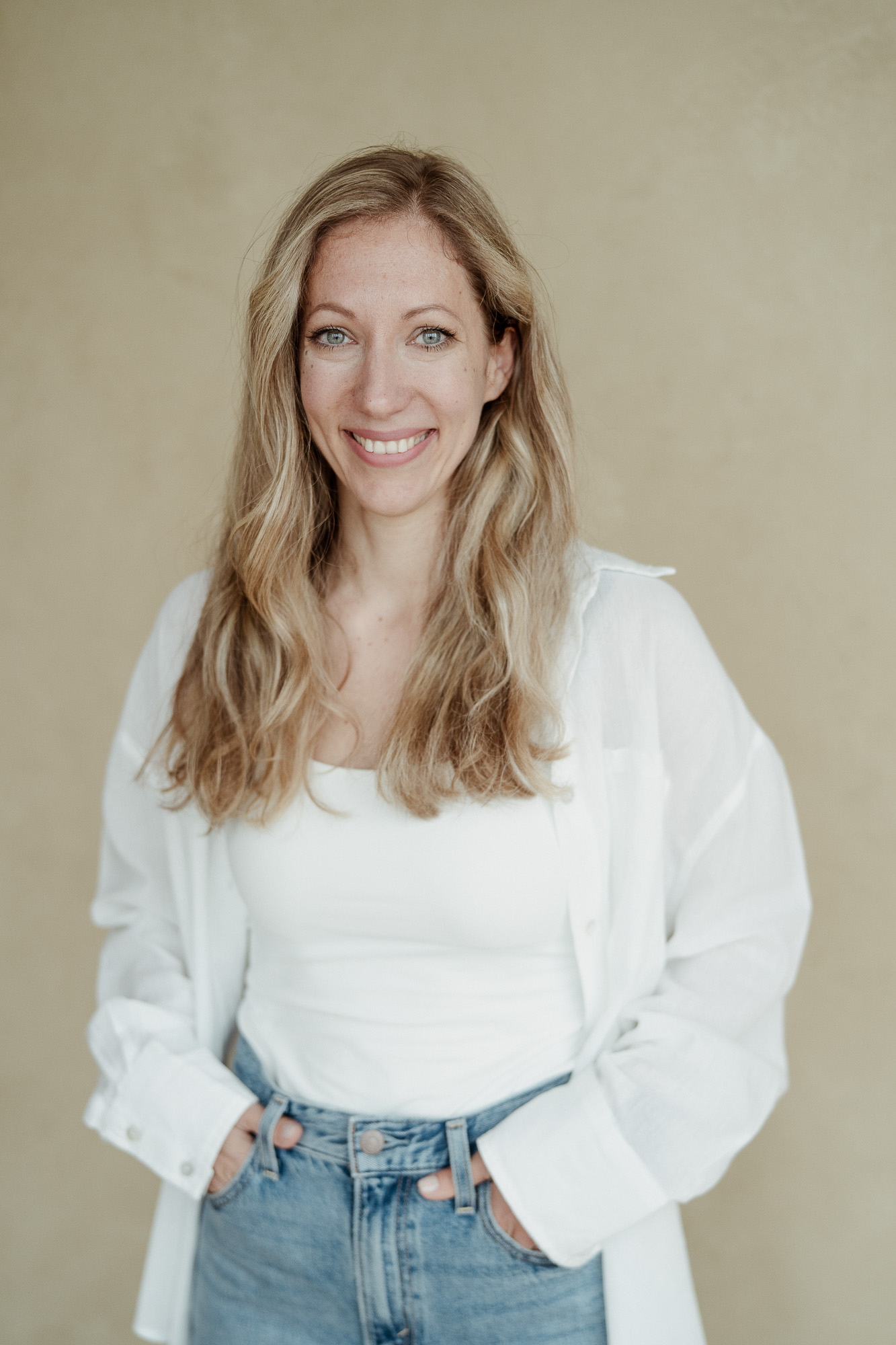 Katharina Musialek lächelt lässig in weißem Hemd und Jeans